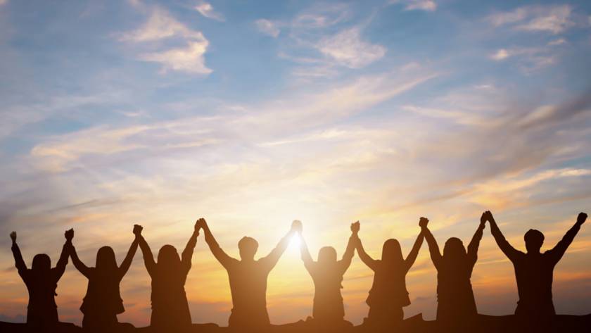 Gruppe von Menschen, die sich an den Händen fassen und gemeinsam die Arme in die Luft strecken
